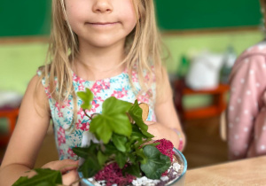 dziewczynka siedzi obok rośliny