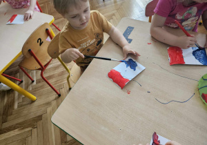 chłopiec maluje farbami flagę Francji, obok dziewczynka