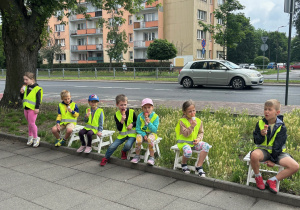 grupa dzieci siedzi na taboretach i je lody