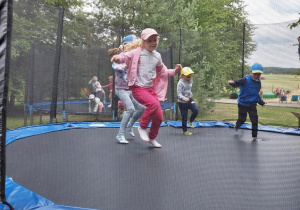 grupka dzieci skacze na trampolinie