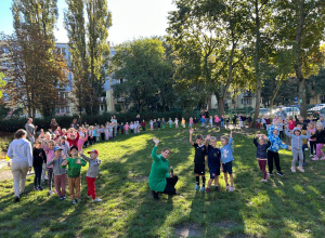dzieci ze wszystkich grup stoją w kolę i machają