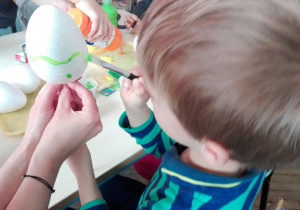 chłopiec maluje jajko styropianowe