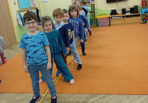 Dzieci stoją nad liną jeden za drugim