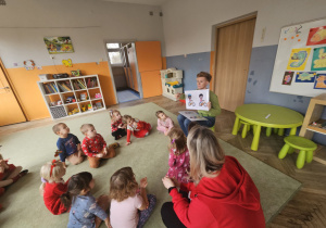 dzieci siedzą w kole. Prowadząca pokazuje obrazki